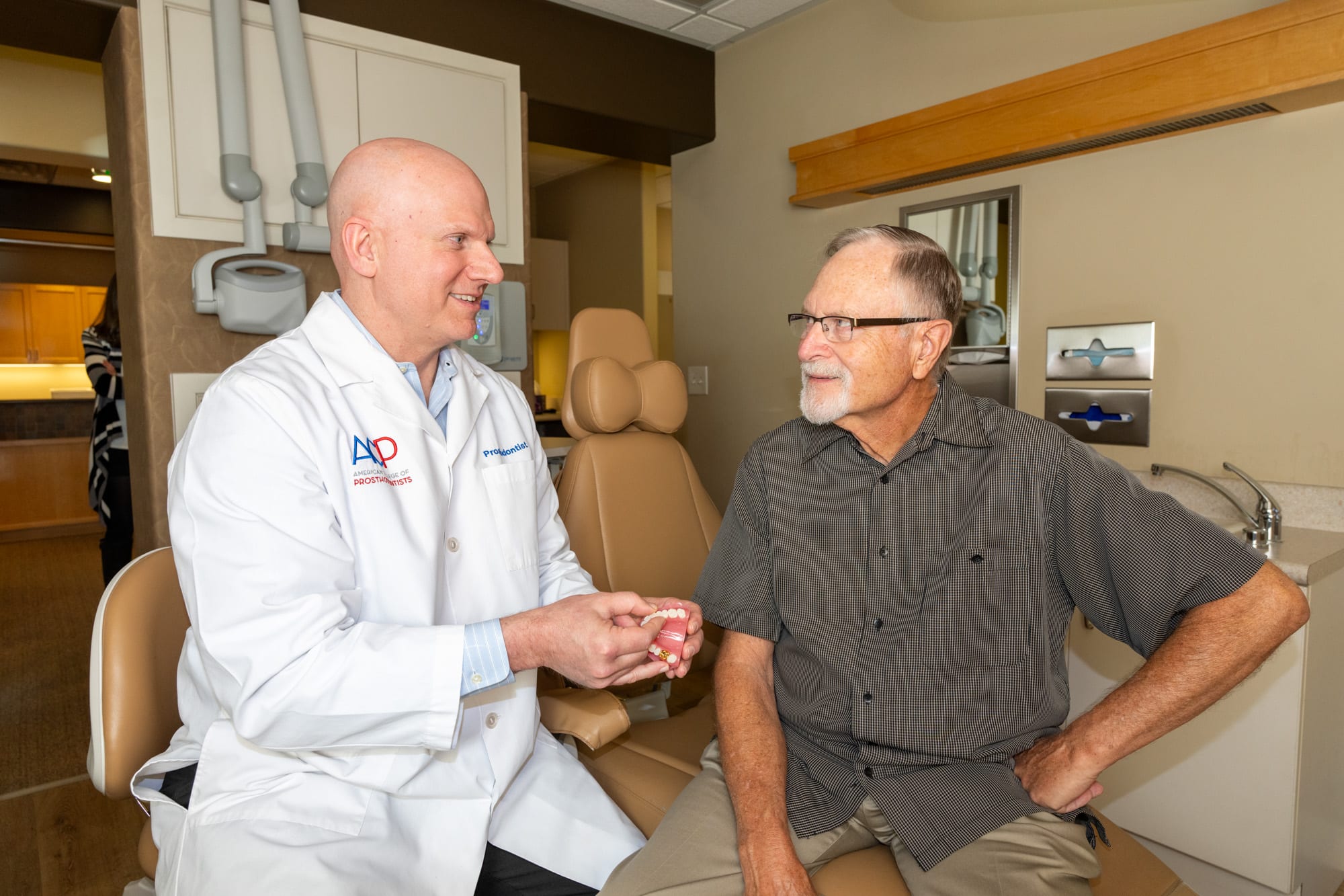 Dr. Andrus showing a patient a tooth model during a smile makeover consultation