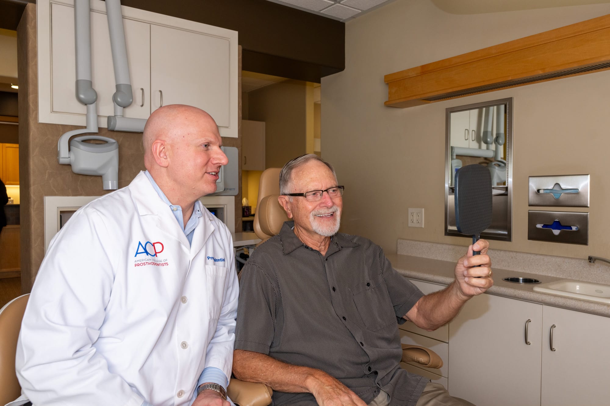 Dr. Andrus reviewing a patient's new smile in a hand mirror chairside